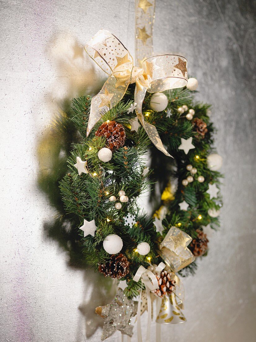 Weihnachtlich dekorierter Kranz mit Schleife an Wand aufgehängt