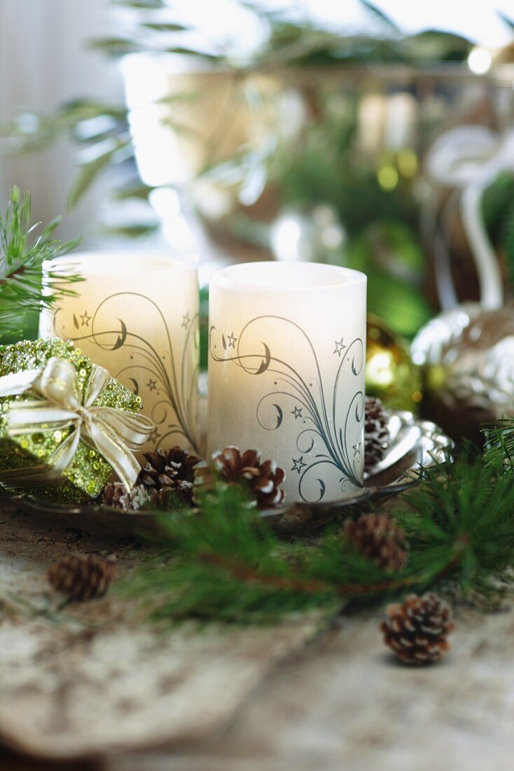 Verzierte Kerzen und kleine Tannenzapfen auf Schale in weihnachtlicher Stimmung
