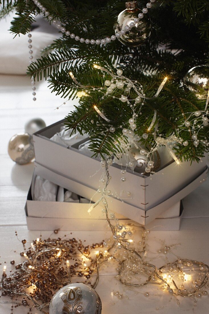 Perlen- und Lichterketten vor und auf Weihnachtsbaum
