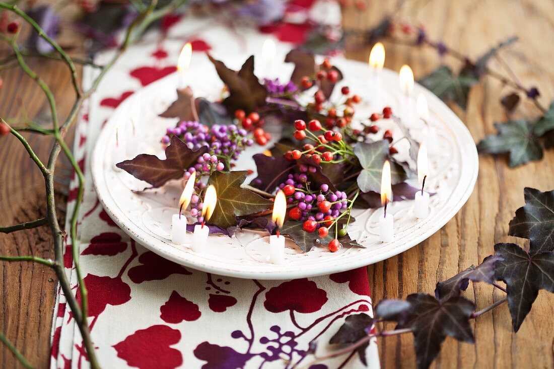 Teller mit Kranz aus Callicarpa, Mini-Hagebutten und lila Efeu und kleinen Kerzen