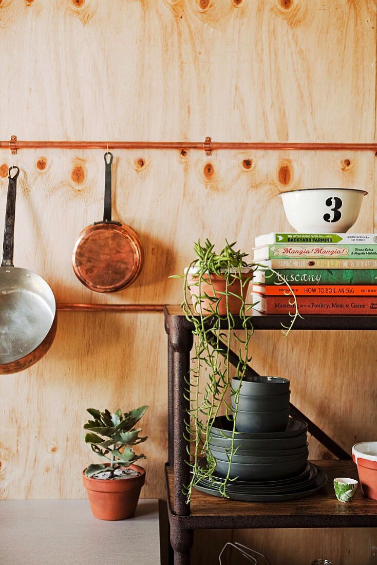 Open shelf made of rusty metal against wooden wall with hanging cookware