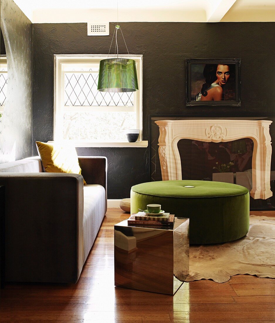 Schieferartig gestaltete Wände in Wohnraum mit Designersofa, grünem Polstertisch und Spiegelwürfel