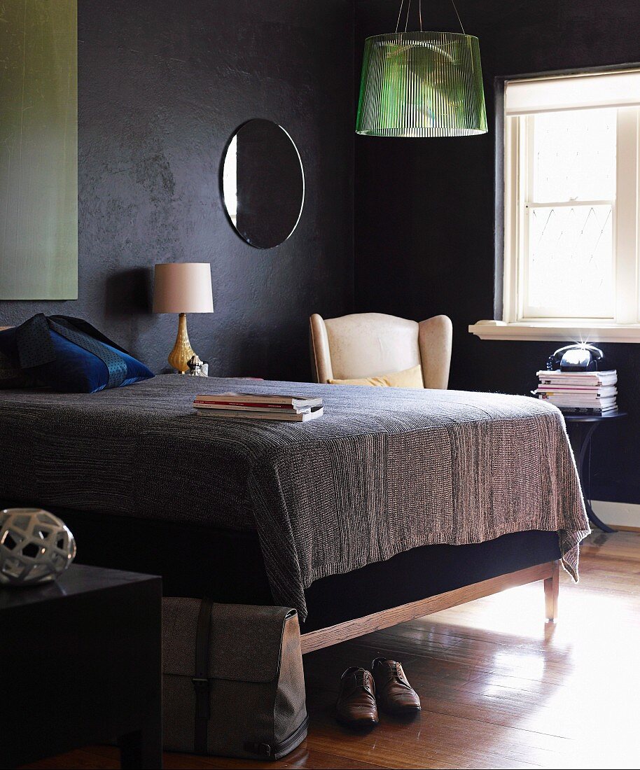 Double bed with tall, upholstered frame in small bedroom with black walls
