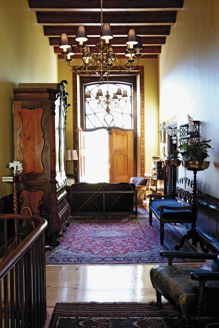Antique furnishings in various styles, Oriental rug and chandelier in narrow, yellow-painted room