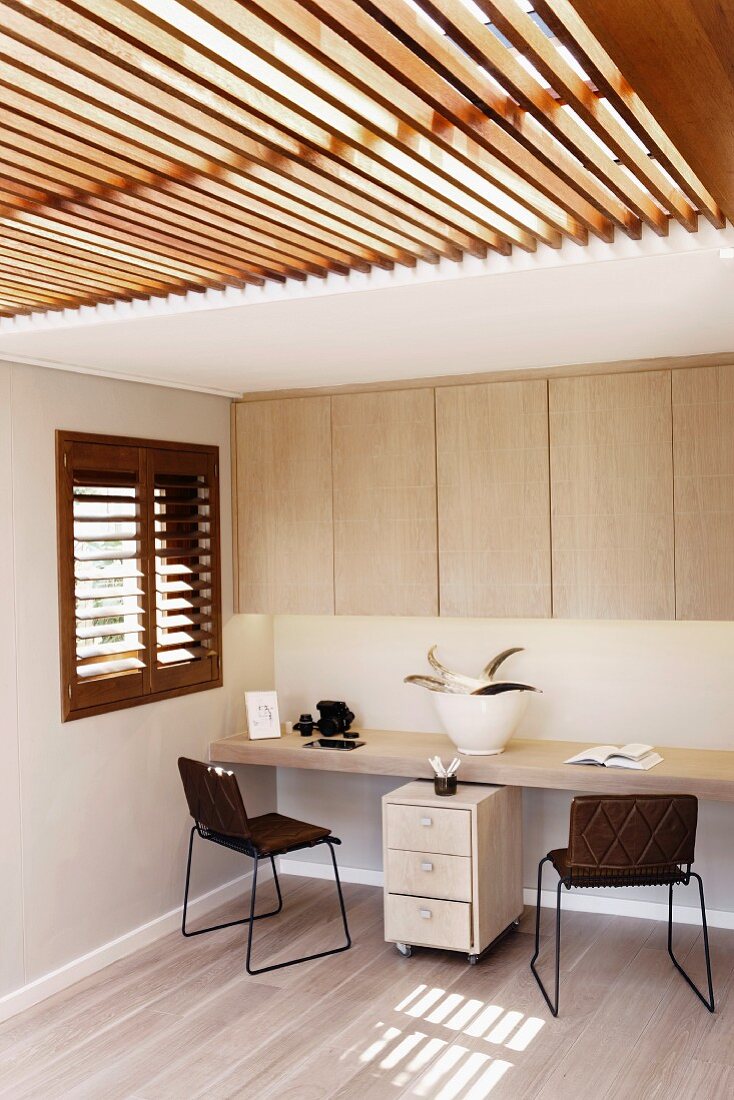 Simple fitted furniture in home office with slatted glass ceiling