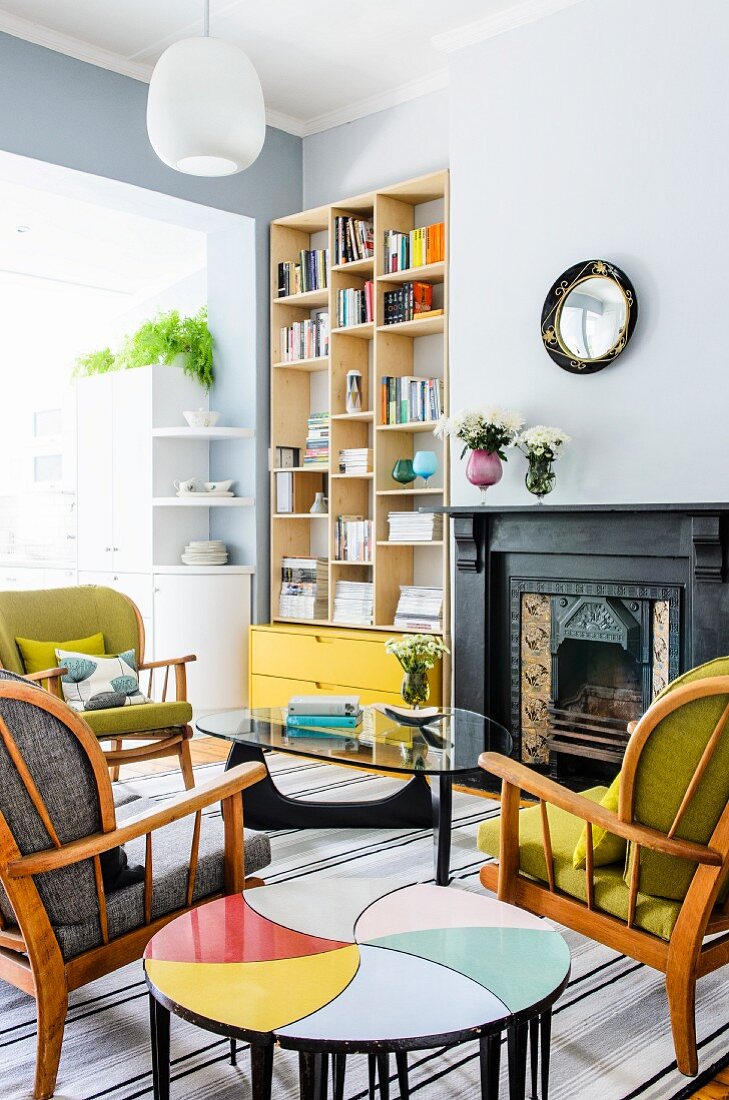 Retro seating area with original side tables; modern bookcase and bright yellow drawers in niche