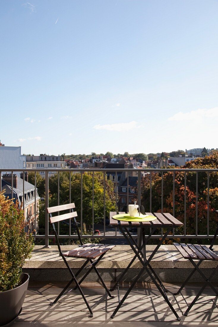 Folding table set on sunny balcony with view over the rooftops of Brussels