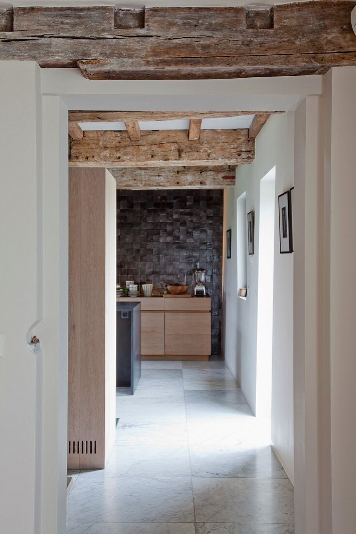 Blick in die Küche entlang einer Gangflucht mit sichtbaren alten Holzbalken in renoviertem Haus