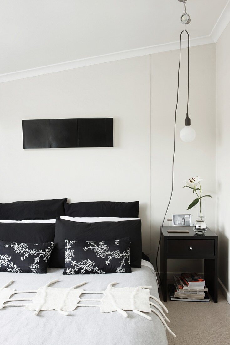 Schlafzimmer mit japanischen Dekokissen und Pendelleuchte an flexibler Roll-Aufhängung