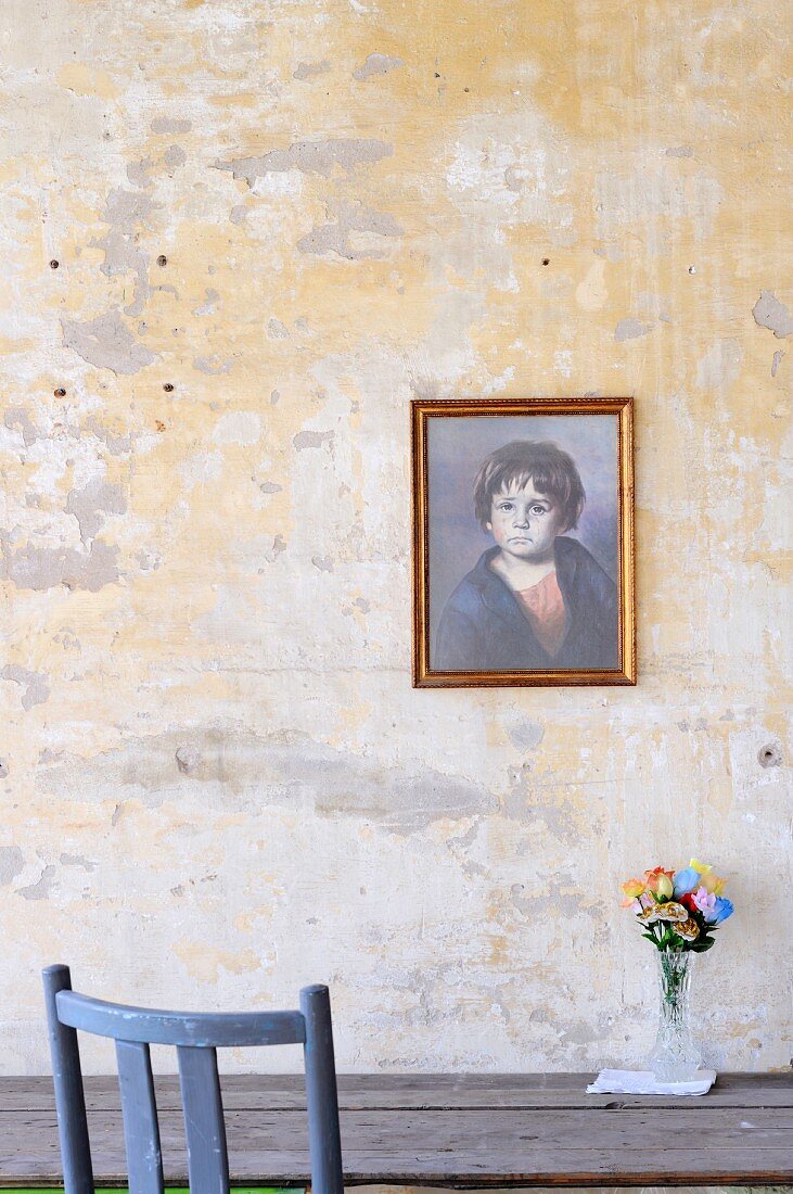 Gemälde eines Kindes an unbemalter Wand über Holztisch