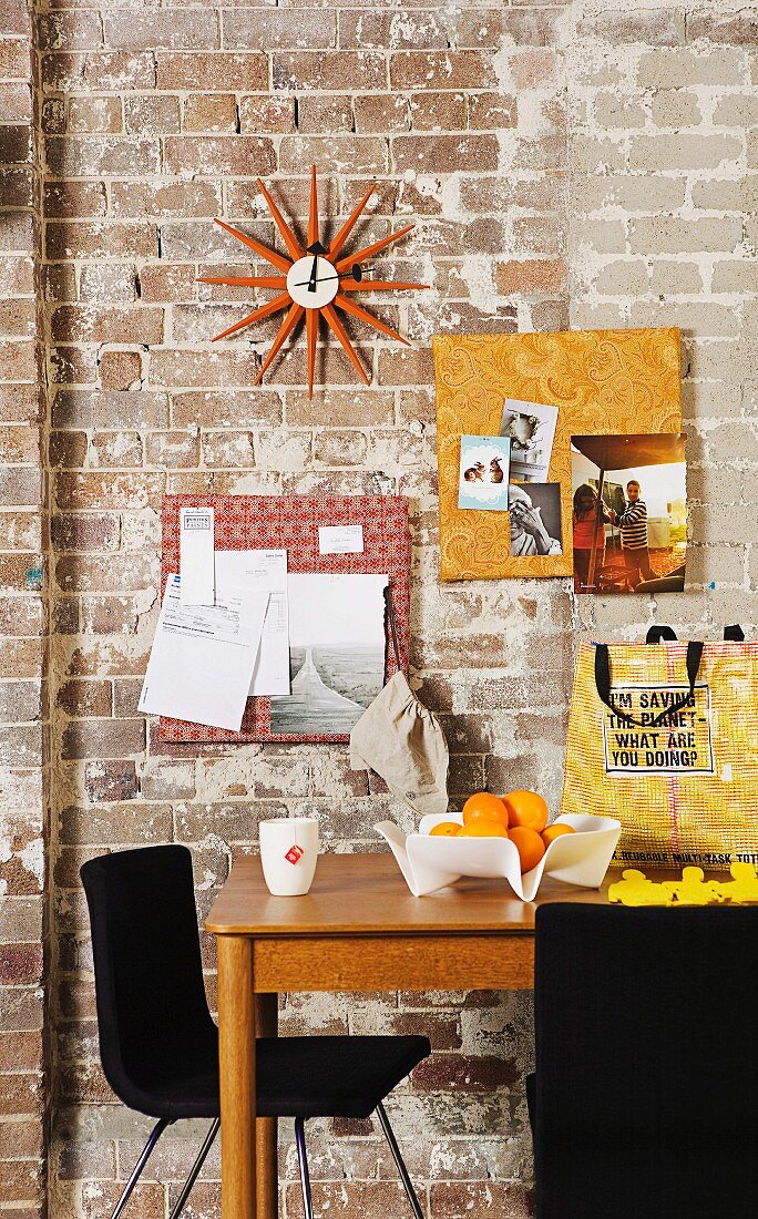50s designer wall clock (Sunburst Clock) and pinboards covered in patterned fabrics decorating brick wall