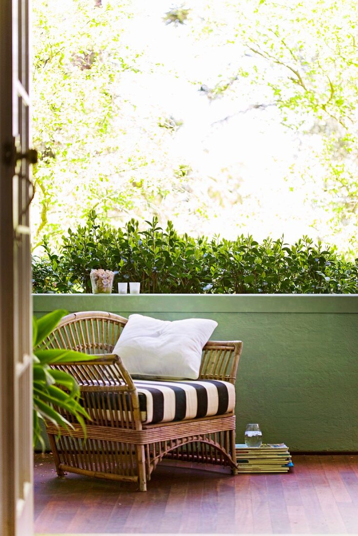 Einladender Bambussessel auf Veranda mit grüner Brüstungsmauer und Edelholzparkett