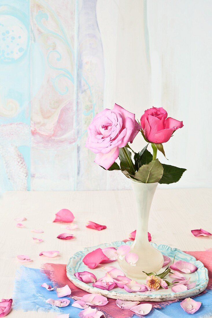 Pinkfarbene Rosen in weisser Blumenvase auf Keramikteller