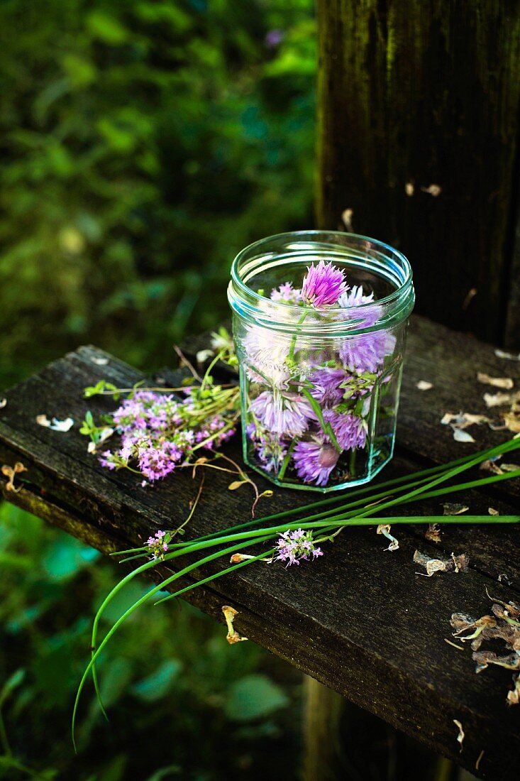 Chive flowers in a screw-top jar on a wooden bench