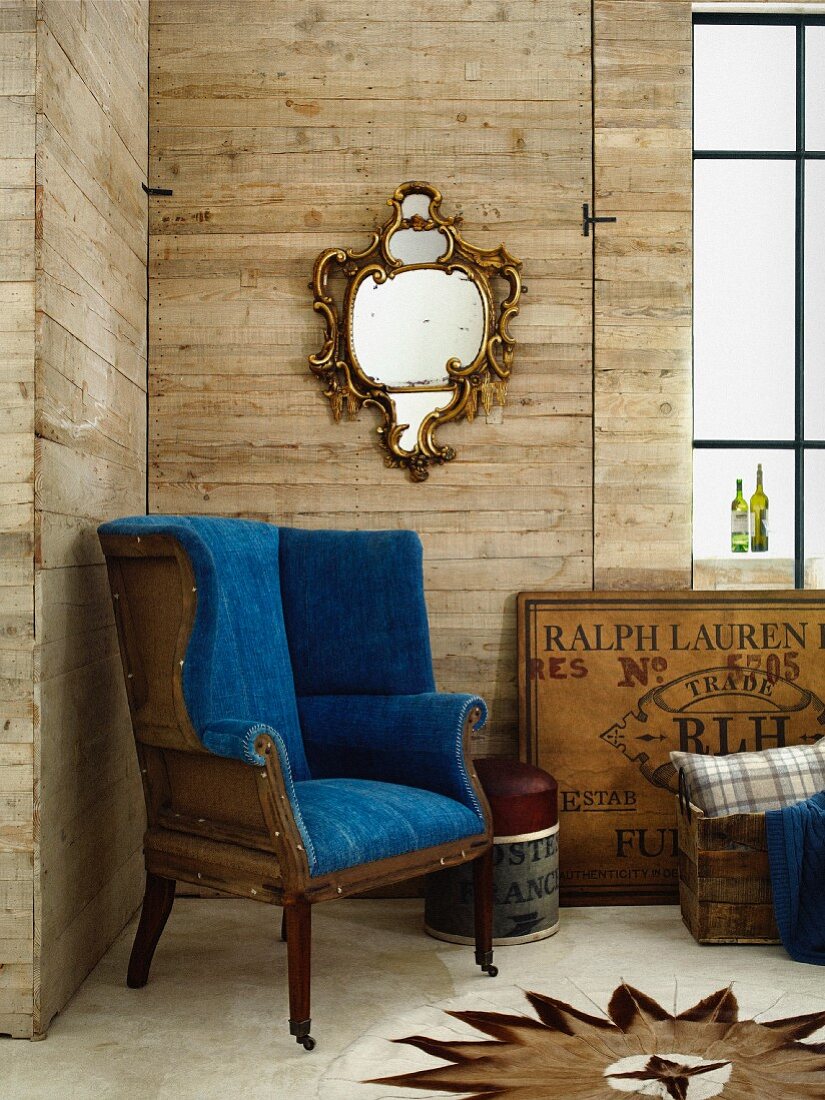 Designer-Sessel mit königsblauem Bezug und italienischer Spiegel aus dem 19. Jahrhundert im Zimmerecke mit Holzwänden