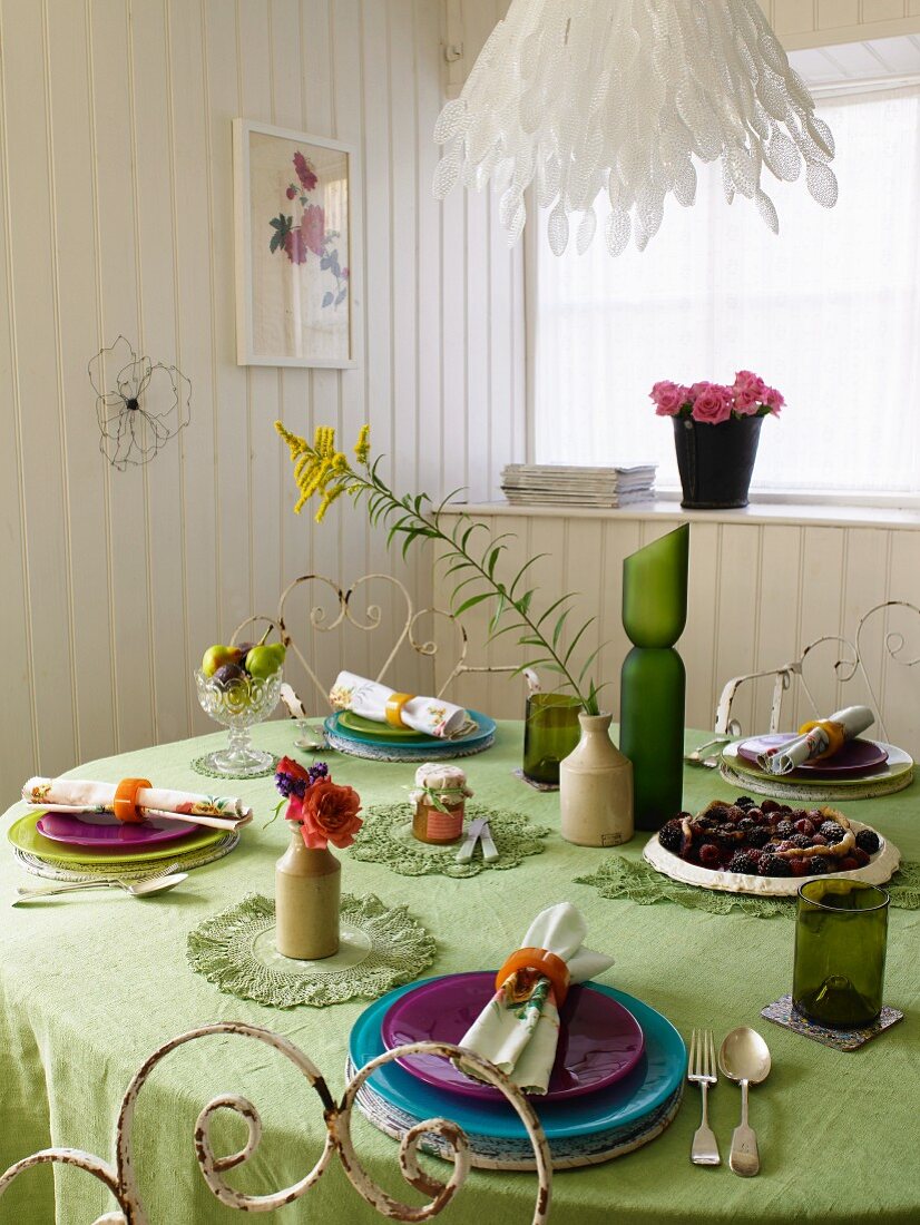 Gedeckter Tisch mit grüner Tischdecke in einem Esszimmer mit weisser Holzverkleidung