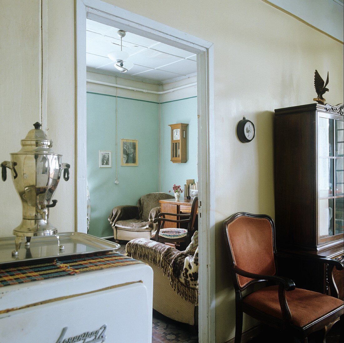 Offener Durchgang mit Blick ins Wohnzimmer zwischen Küchenschrank mit Samowar und antikem Armlehnstuhl in Esszimmer