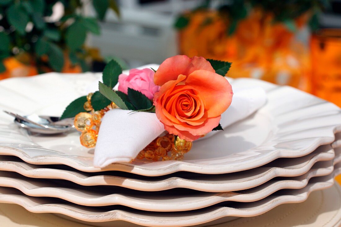 Serviette with roses as a serviette ring on stacked plates