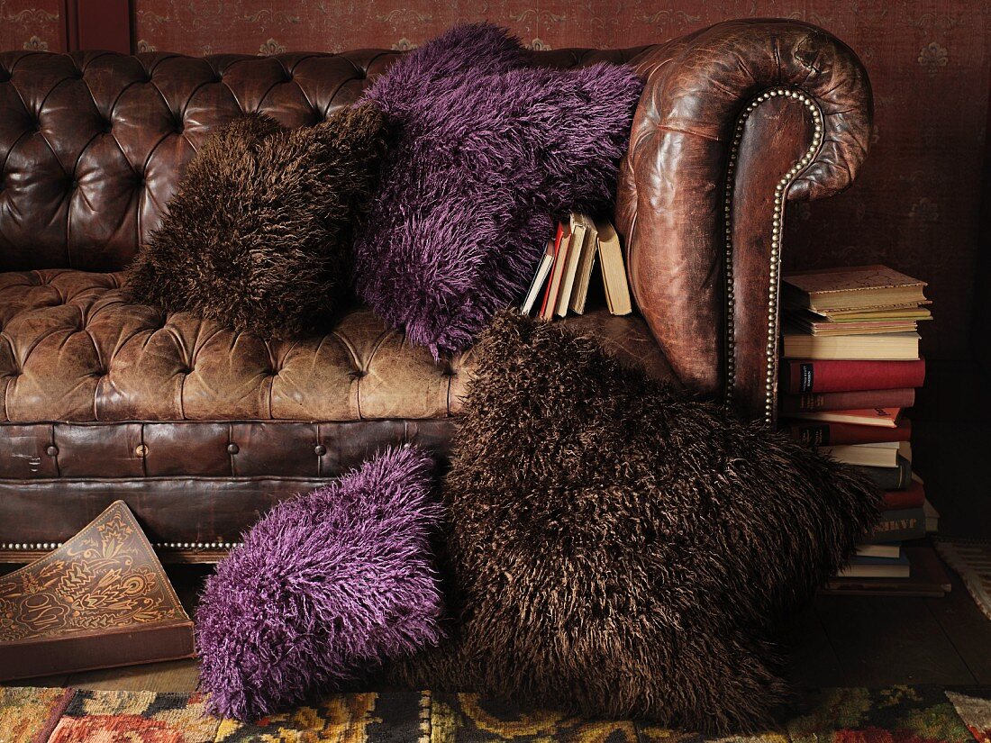 An old leather sofa with decorative cushions in brown and purple