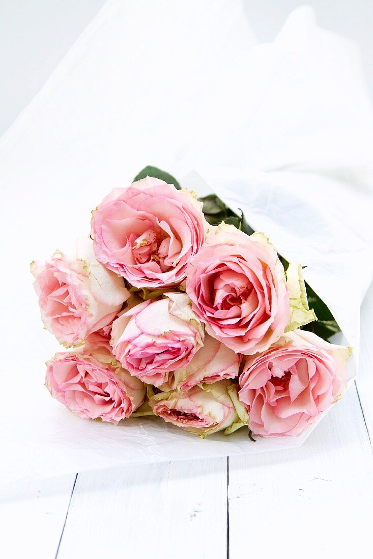Bouquet of pink roses in silk paper on white painted wood boards