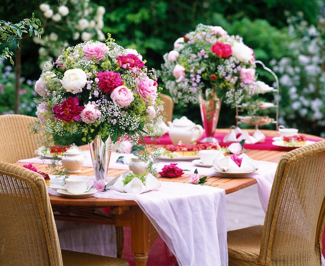 Festlicher Blumenstrauss aus Pfingstrosen und Schleierkraut auf gedecktem Tisch