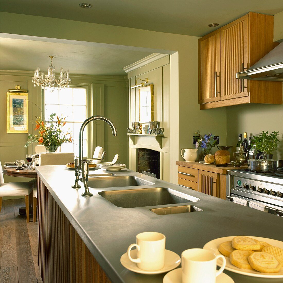 Küche im Landhausstil mit pastellgrünen Wänden, Holzmöbeln, offenem Kamin und Essplatz