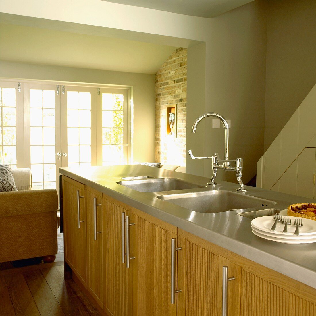 Küche im Landhausstil mit pastellgrünen Wänden, Holzmöbeln und Mittelblock mit Spülbecken