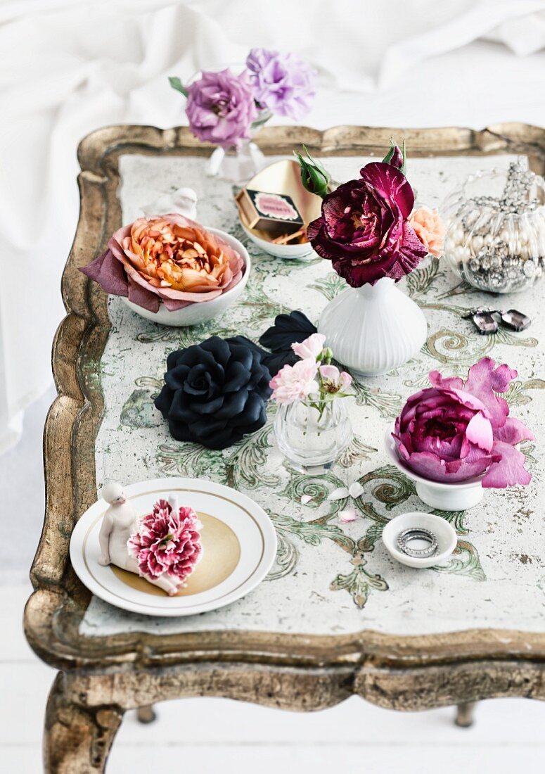 Boudoir-Look; Rosenblüten in kleinen Vasen und verstreuter Schmuck auf Antik-Tablett