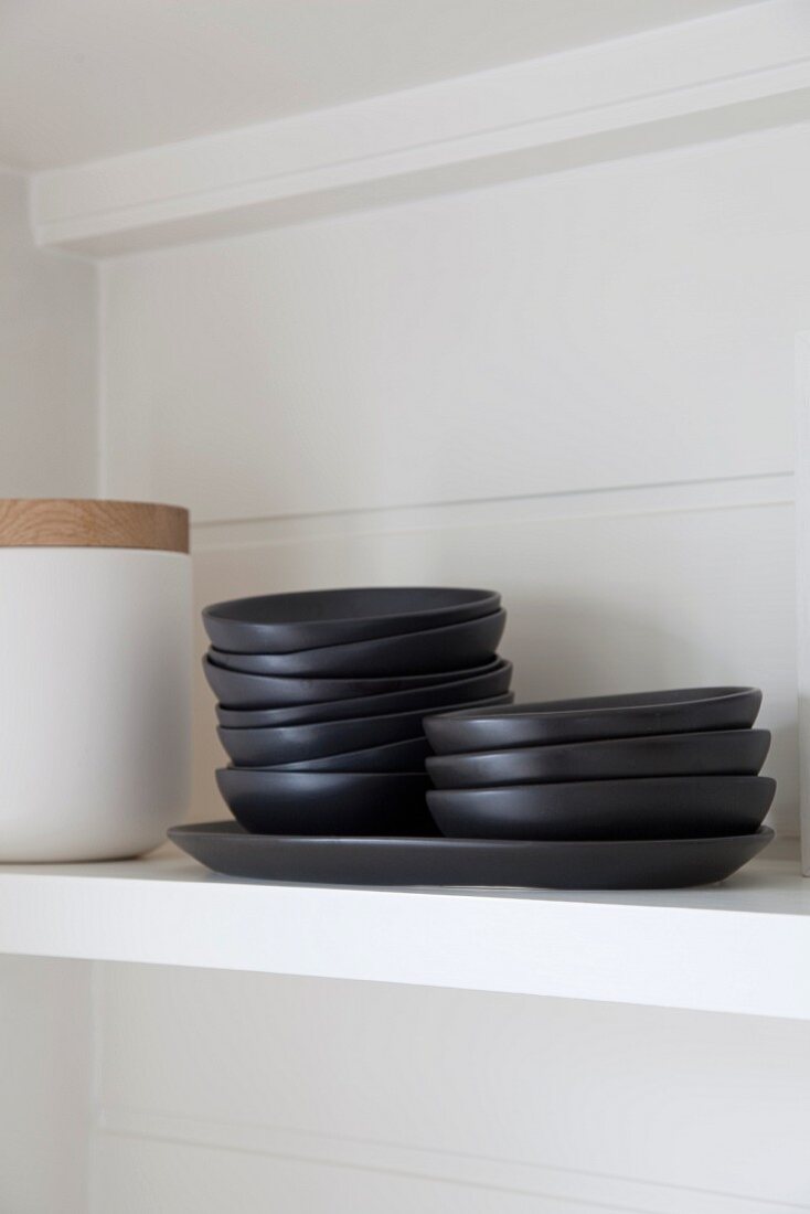 Black dishes on white shelf