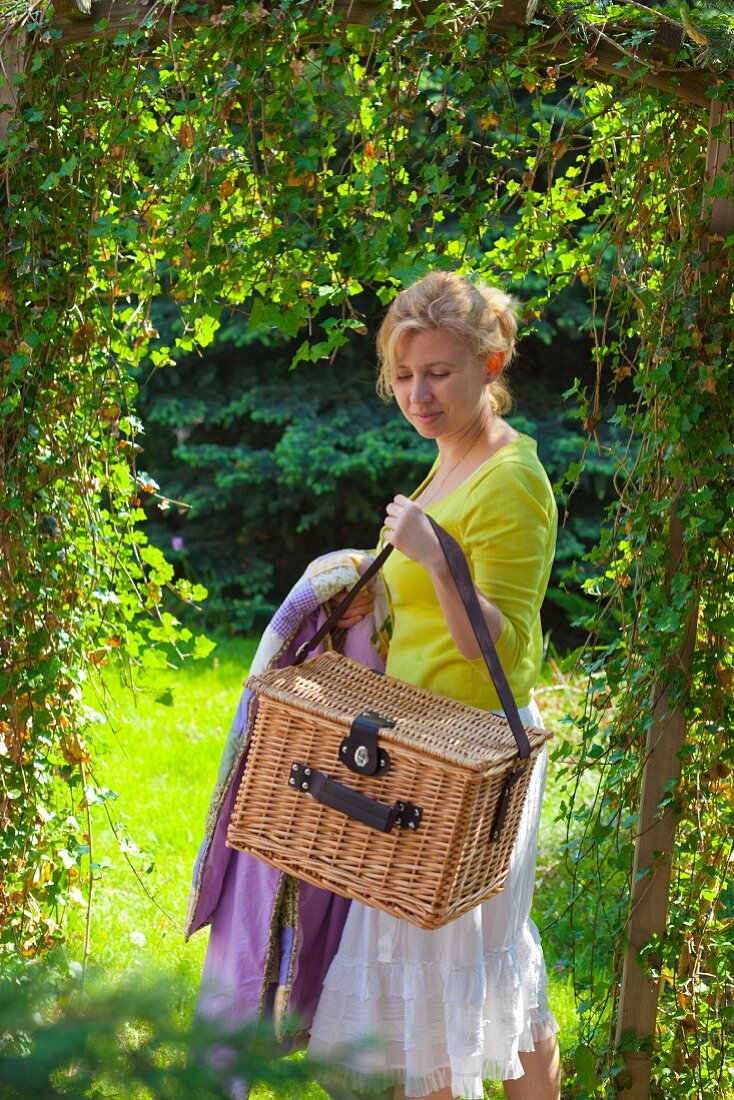 Frau mit Picknickkorb im Garten