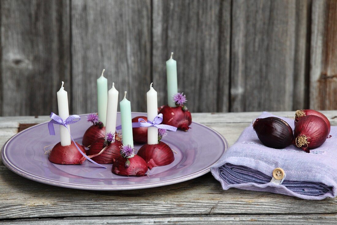 Halbierte rote Zwiebeln als Kerzenständer und Säckchen mit Leinenservietten