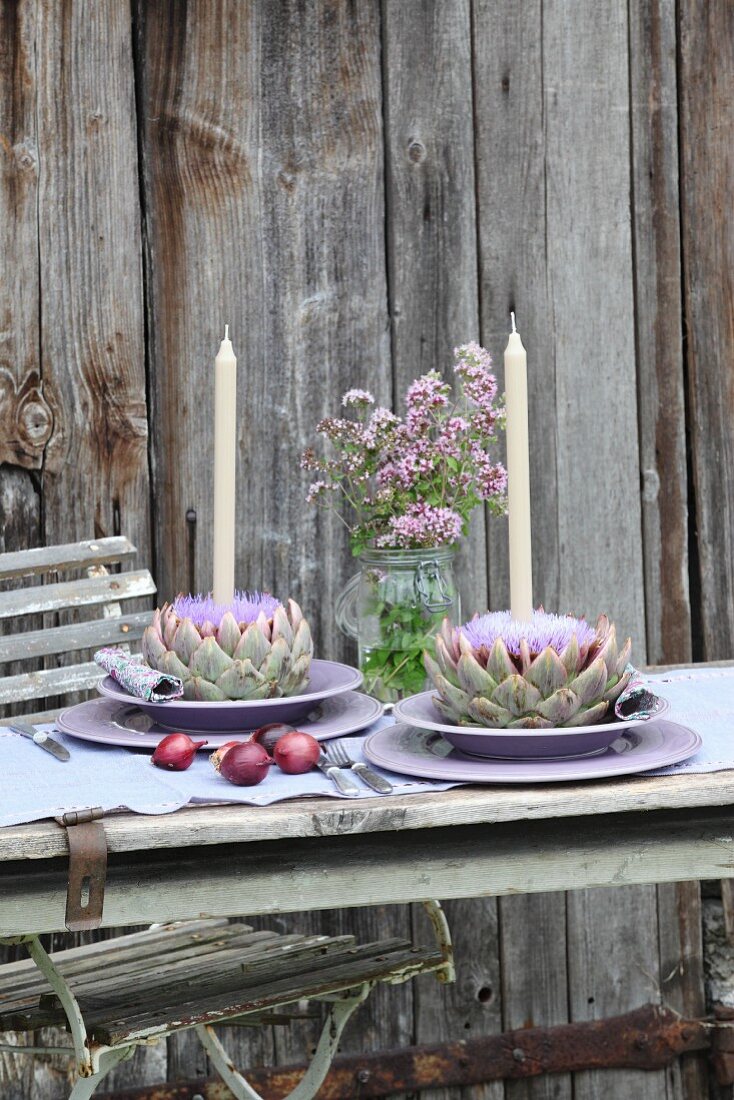 Tischgedecke mit Kerzen in Artischockenblüten, Majoranblüten im Weckglas