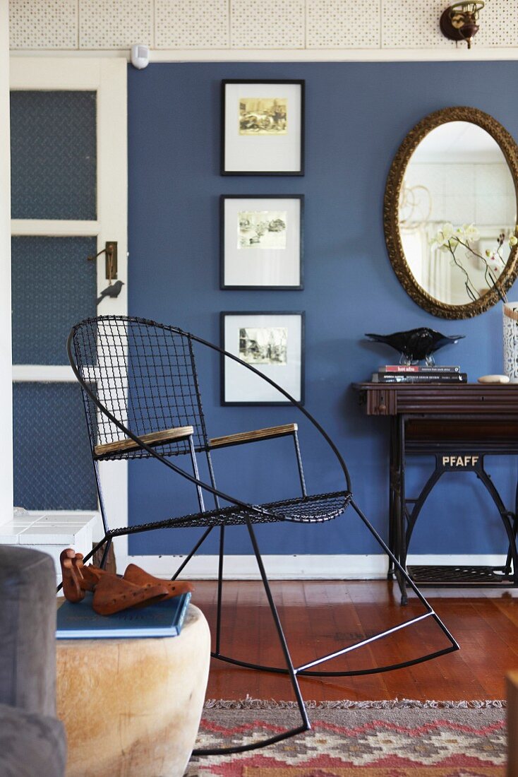 Schwarzer Vintage Schaukelstuhl aus Metall vor blau getönter Wand in traditionellem Wohnzimmer