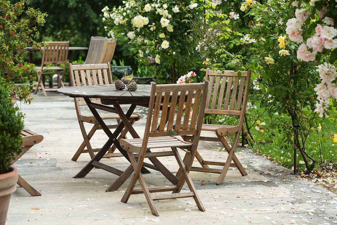 Gartentische und -stühle aus Holz im Rosengarten