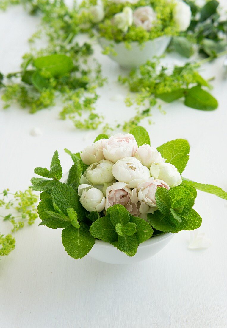 weiße Rosen und Minzeblätter als Gesteck in Porzellanschüssel