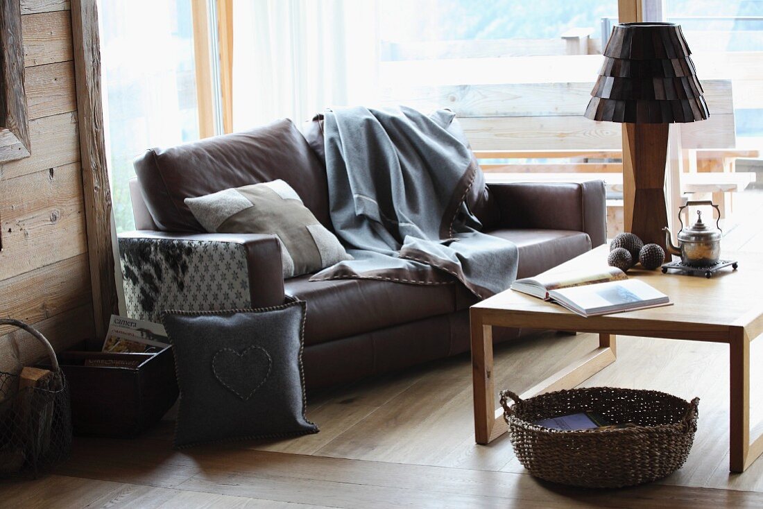 Moderne Landhausatmosphäre in Sitzecke mit selbstgenähten Kissen und Decke auf einem Ledersofa