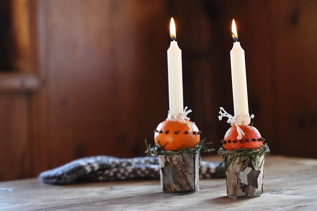 Hand-crafted Advent arrangement of candlesticks made from beakers and oranges stuck with cloves