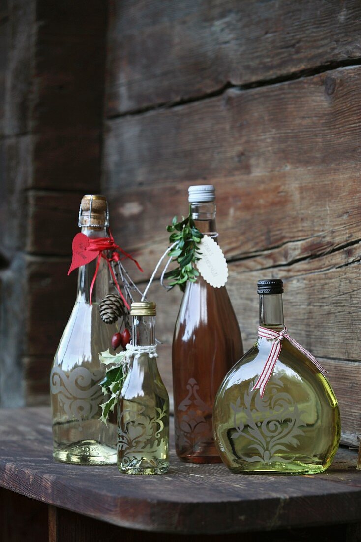 Mit Ornament, Anhängern und Bändchen als Geschenk verzierte Flaschen mit Sekt und Wein