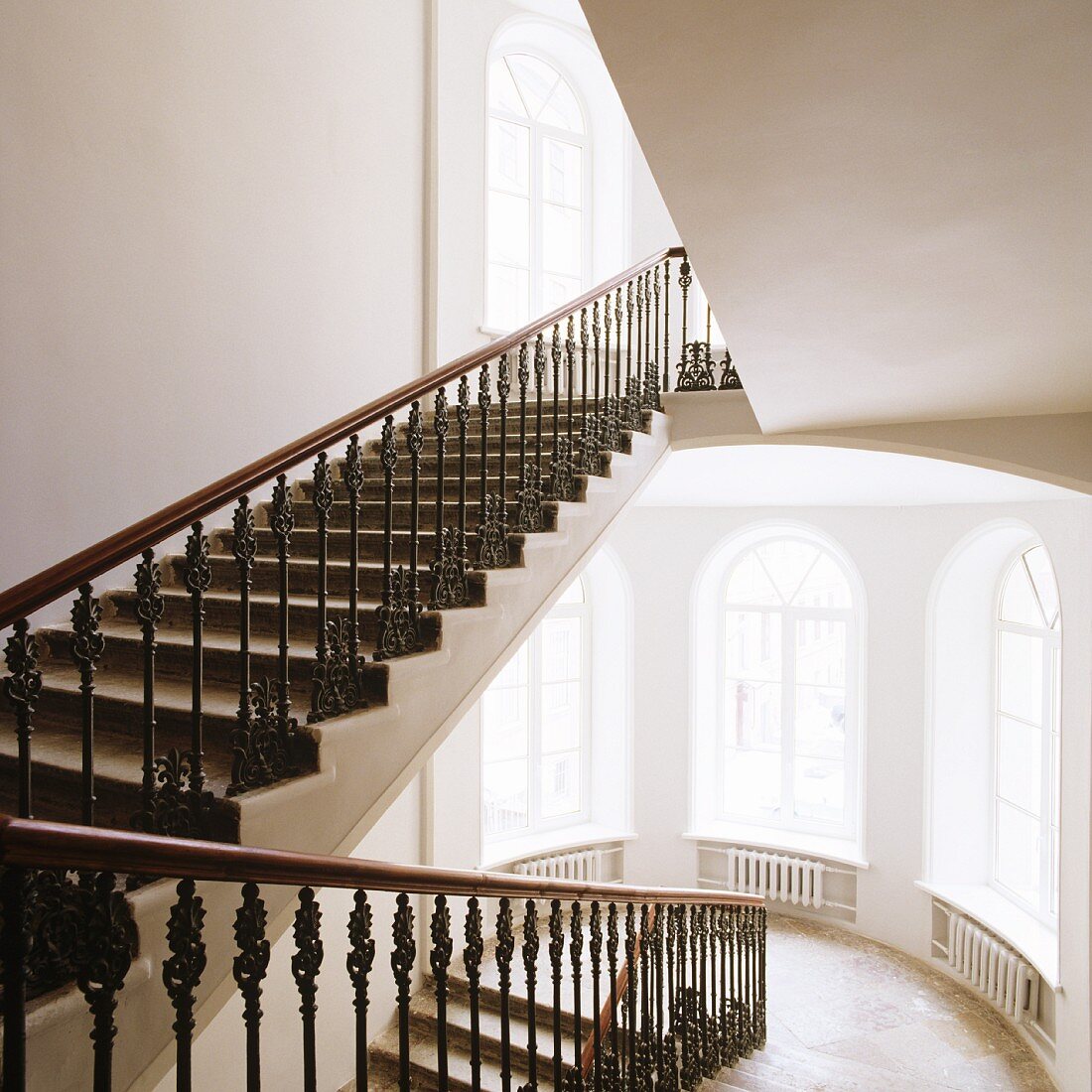 Herrschaftliches Treppenhaus - Schmiedeeisernes Geländer an Treppenlauf und hohe Rundbogenfenster auf Podestebene