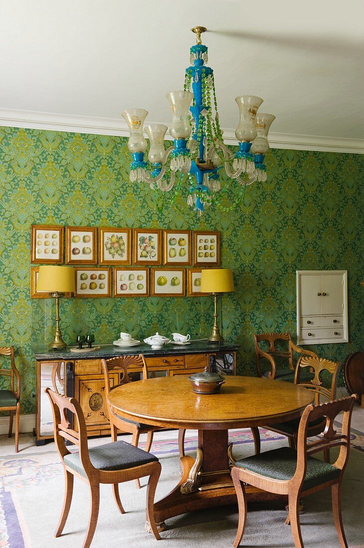 Dining area with antique, English furniture, chandelier & floral patterned wallpaper