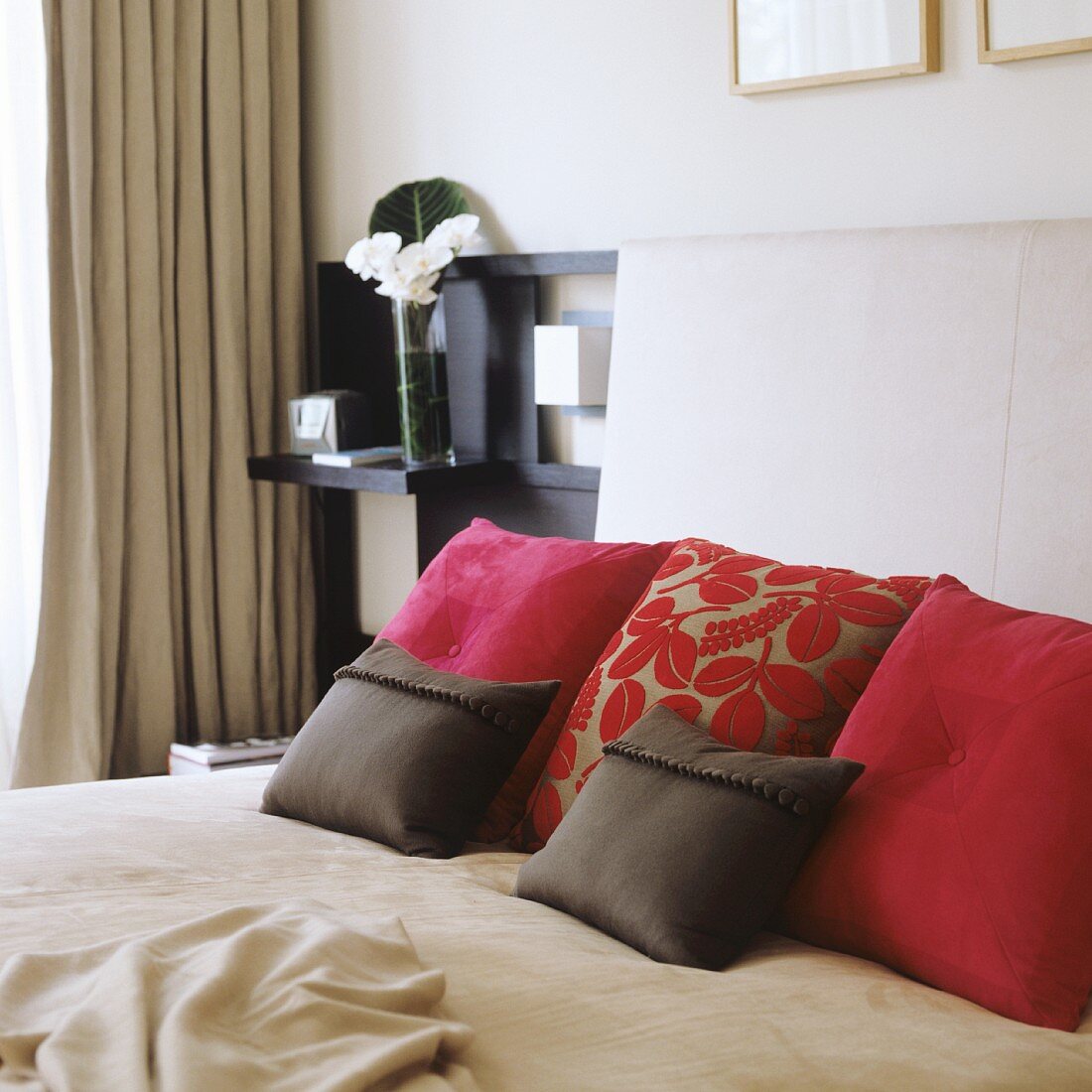 Scatter cushions on double bed with upholstered headboard in modern bedroom