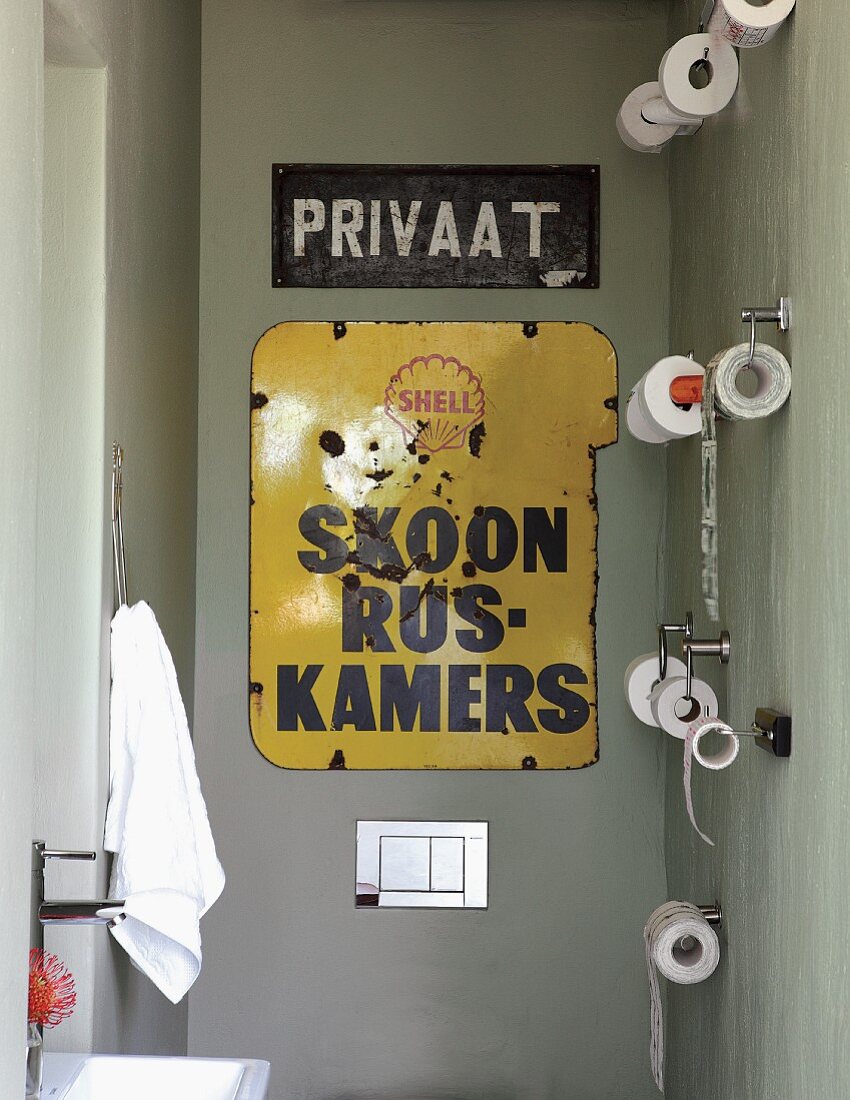 Guest toilet decorated with metal signs & multiple toilet roll holders