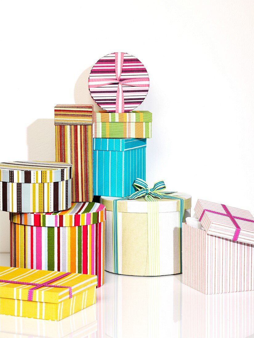 Stacked, striped, decorative boxes of various sizes, shapes and colours embellished with ribbons
