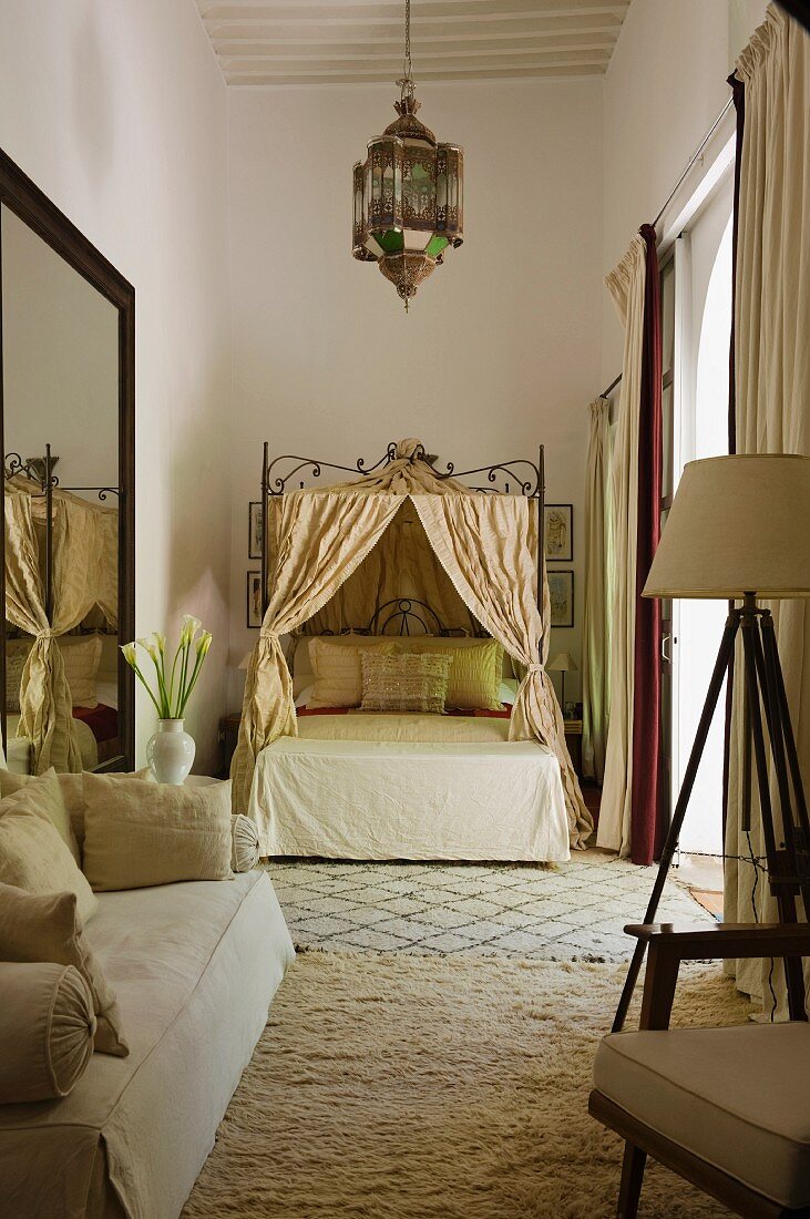 Marokkanisches Schlafzimmer in Cremetönen mit Sofa, Himmelbett und Laternenleuchte