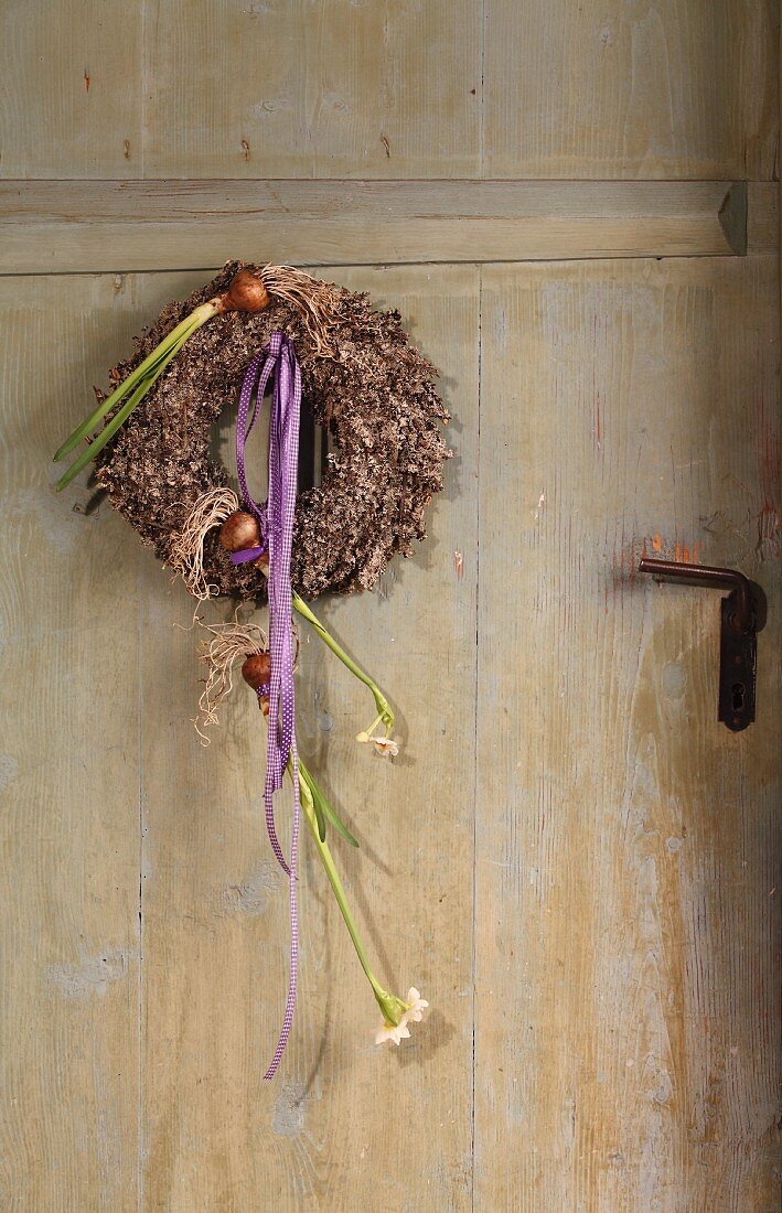 Wreath with flower bulbs and ribbons on vintage front door