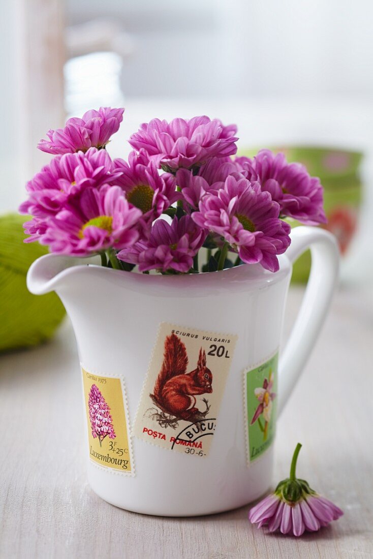 Flowers in jug decorated with postage stamps