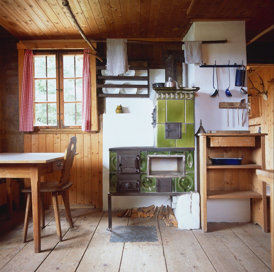 Rustikale Küche und Hauswirtschaftsraum mit Kachelofen und breiten rohen Holzdielen