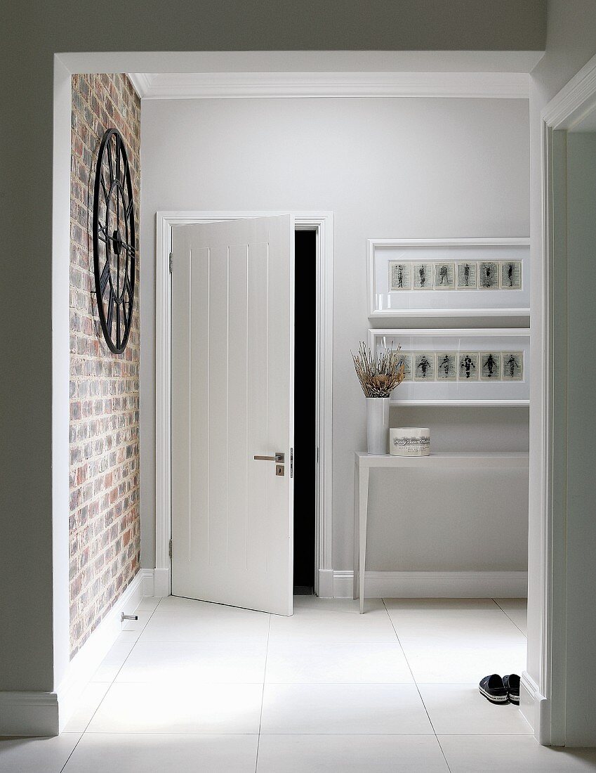 Foyer with white floor and brick wall to one side