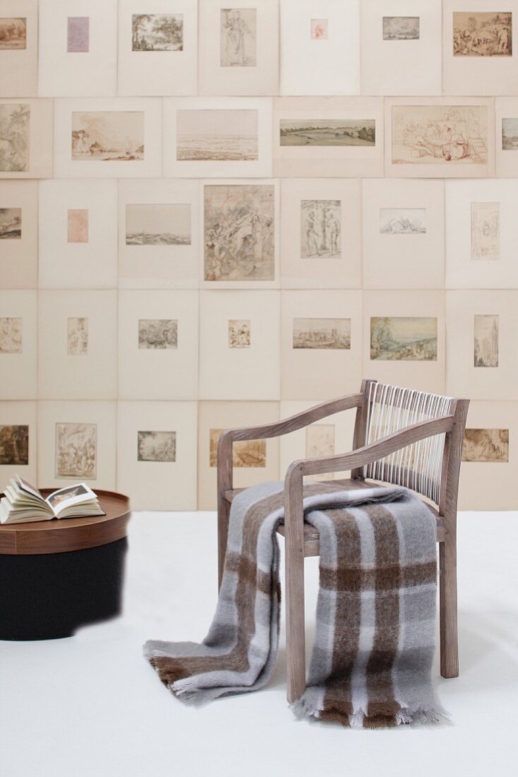 Blankets on armchair in front of numerous unframed etchings on wall