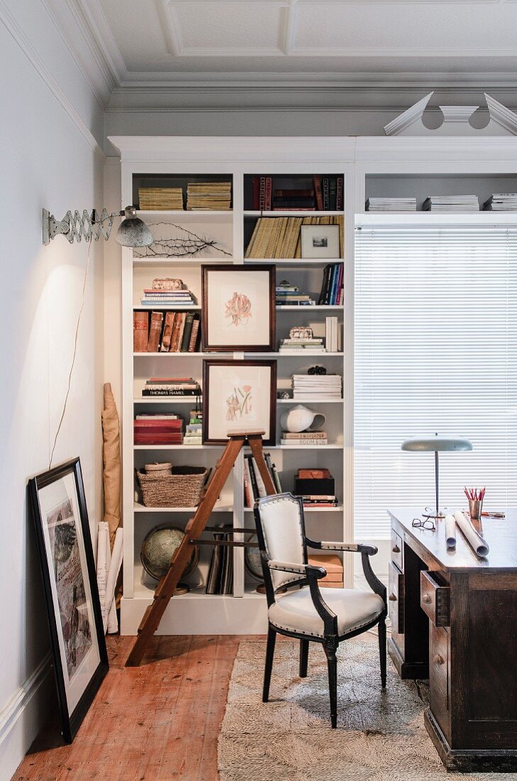 Antique desk and chair in front of partially open-fronted shelving in traditional study